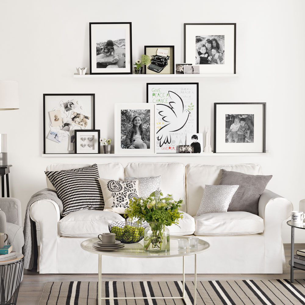 White living room with picture ledges with framed prints above white sofa