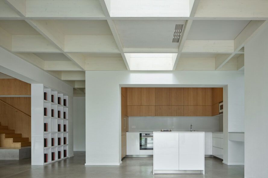 A kitchen with white walls, ceilings, floors and counters. The cabinets are a light-toned wood.